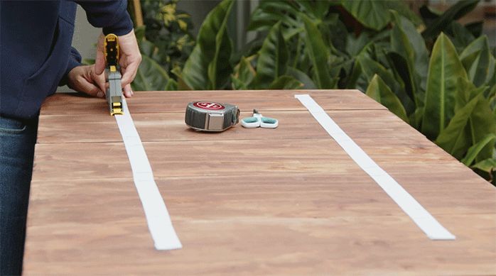 una persona fija un elástico en los trozos de madera para crear una cubierta desmontable.