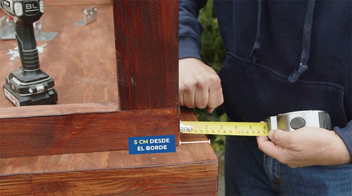 una persona mide 5 cm con una huincha de medir para posicionar la base en la mesa.