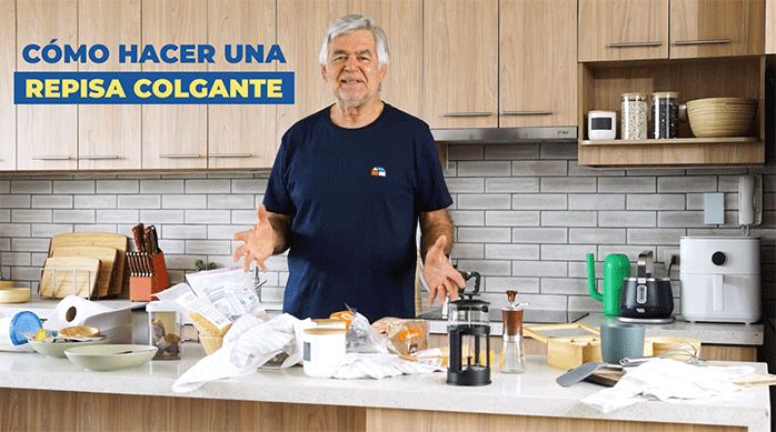 un hombre frente a un mesón de cocina lleno de elementos desordenados, listo para enseñarte a cómo hacer una repisa colgante para la cocina.