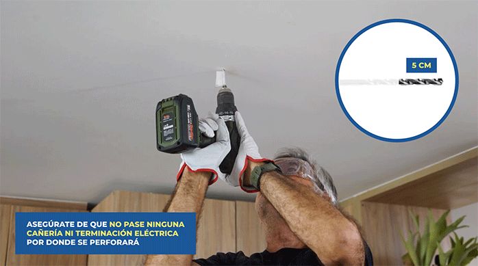 un hombre perfora el cielo de una cocina usando una broca marcada a 5 cm desde la punta.