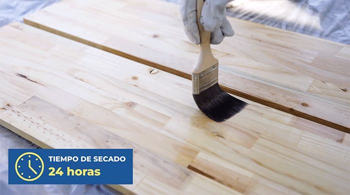 una persona protege la madera de las repisas aplicando barniz marino con una brocha.