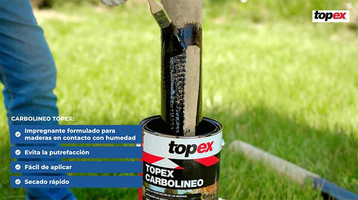una persona aplica carbolineo impregnante en un polín, sumergiéndolo en el tarro y con una brocha.