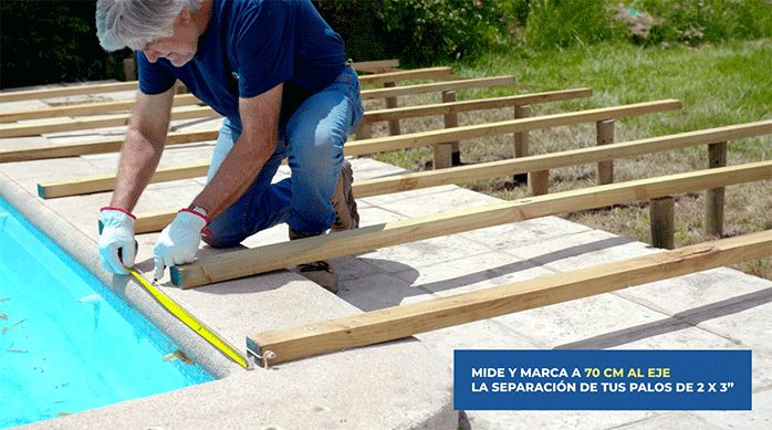 un hombre mide la distancia que debe dejar entre el primer palo de la estructura del deck y el segundo.