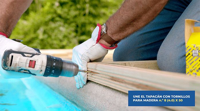 una persona instala un tapacán en el borde del deck que da a la piscina.