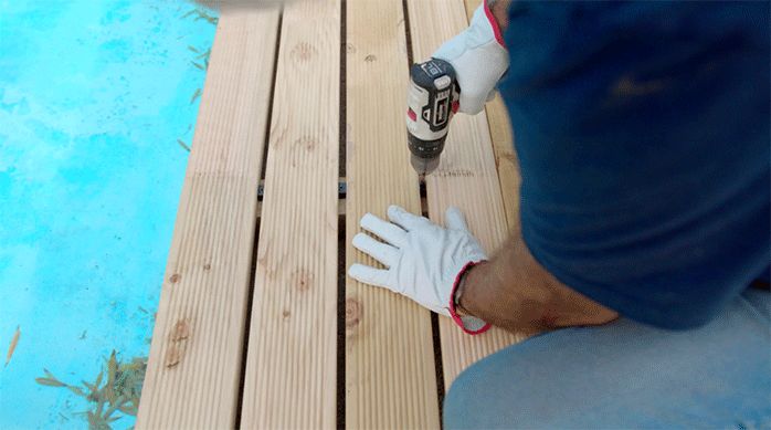 un hombre fija el kit de deck de madera para piscina usando las piezas de sujeción.