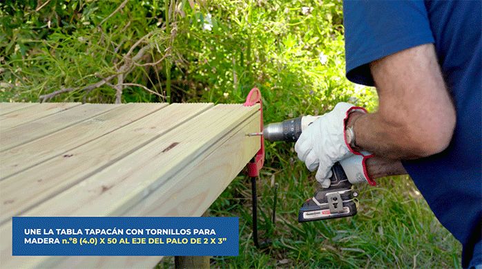 un hombre fija la tabla tapacán en el borde posterior del deck de madera usando un desatornillador y tornillos.