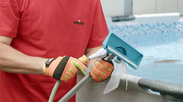 una persona instala un limpiafondo en la manguera del patio.