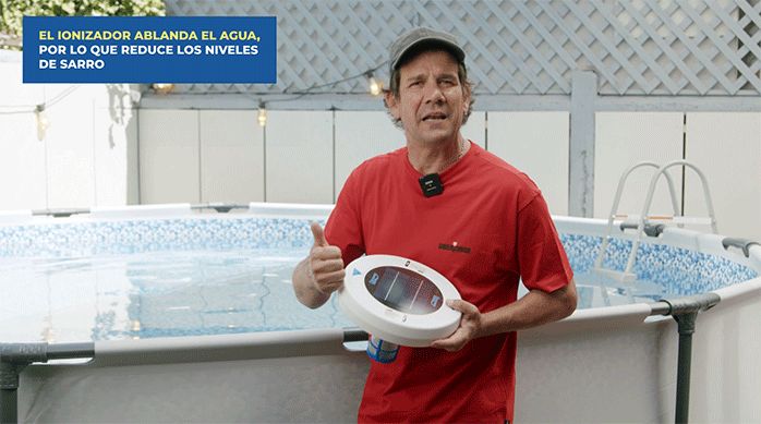 un hombre sostiene un ionizador frente a una piscina estructural.