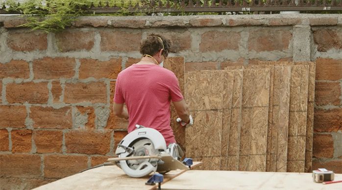 un hombre dispone de manera ordenada varios tableros de osb recién cortados con la sierra circular.