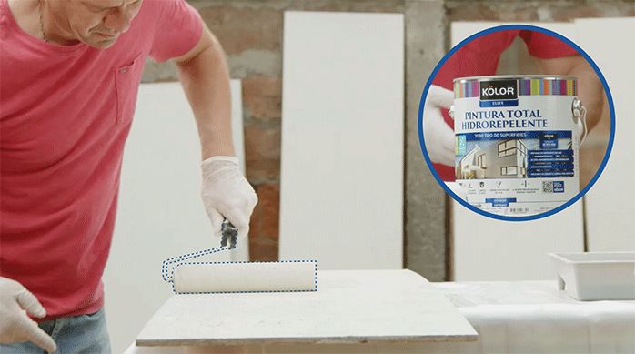 un hombre pinta un tablero de osb con pintura hidrorrepelente usando un rodillo de fibra.