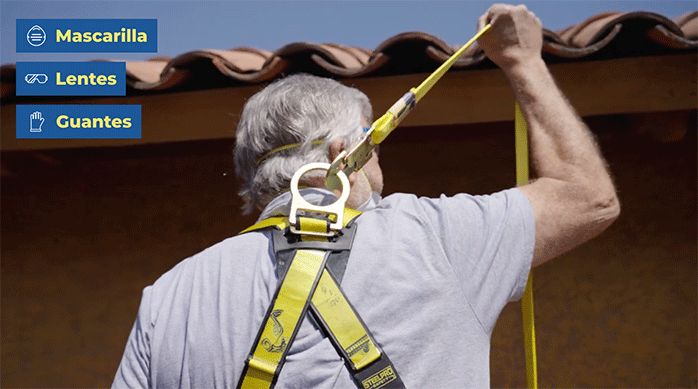 un hombre adulto mayor con un arnés y un cabo de vida para subirse a un techo.