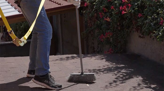 un hombre limpia un techo usando un escobillón.