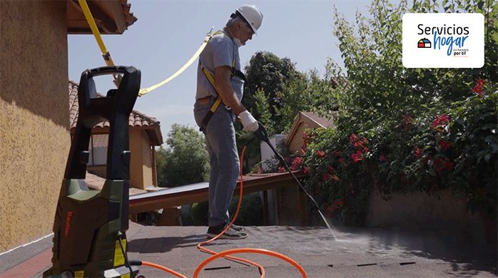 un hombre limpia un techo usando una hidrolavadora.