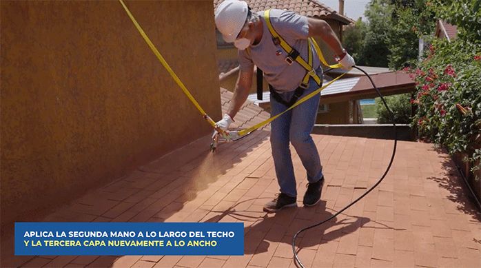un hombre aplica sellador para techos coolguard usando una pistola para pintar sin aire.