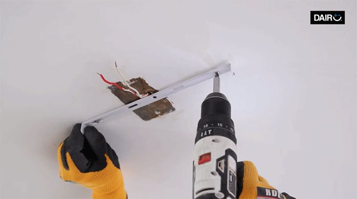 una persona fija el soporte de un panel led en el cielo de una habitación.