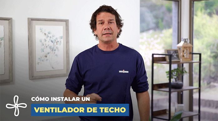 un hombre en un living listo para enseñar cómo instalar un ventilador de techo.