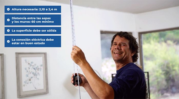 un hombre mide la altura de un cielo en un living, junto a una lista de requisitos para instalar un ventilador de techo.