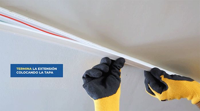 una persona pone la tapa de una canaleta que lleva por dentro los cables eléctricos.