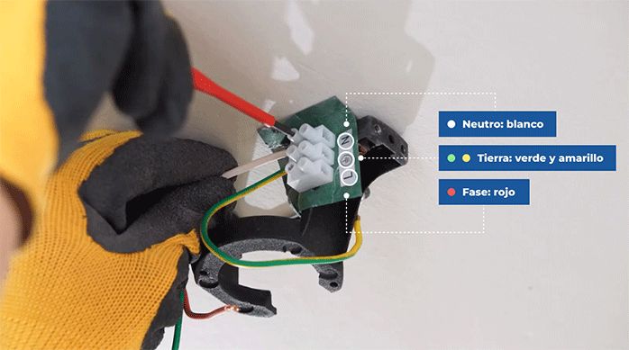 una persona hace la conexión de los cables en la regleta del ventilador de techo.