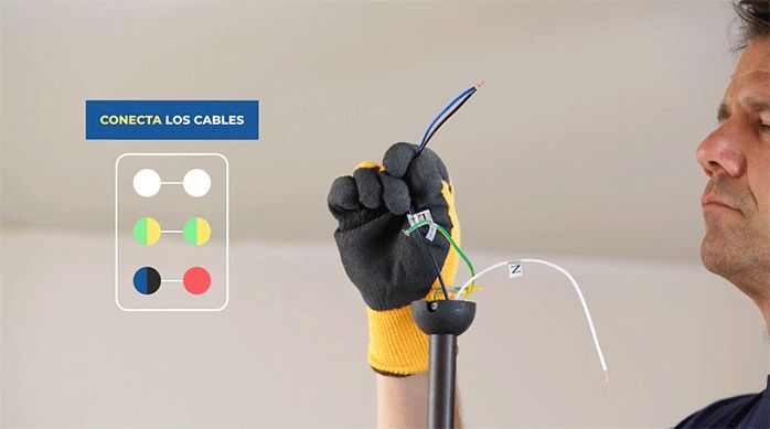 un hombre sostiene los cables de conexión eléctrica del ventilador de techo.