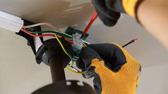 un hombre conecta los cables eléctricos del ventilador a los de la casa.