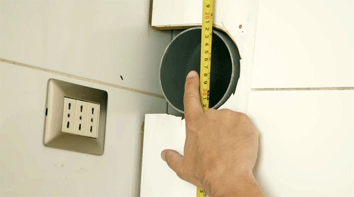 un hombre mide el ducto de ventilación de la cocina.
