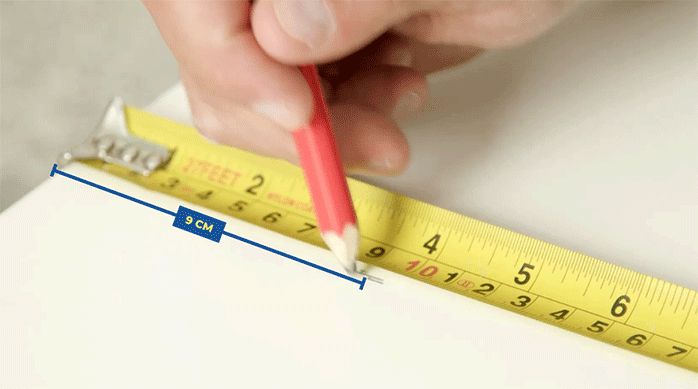 una persona marcando 9 cm en un mueble de melamina para colocar la campana de la cocina.