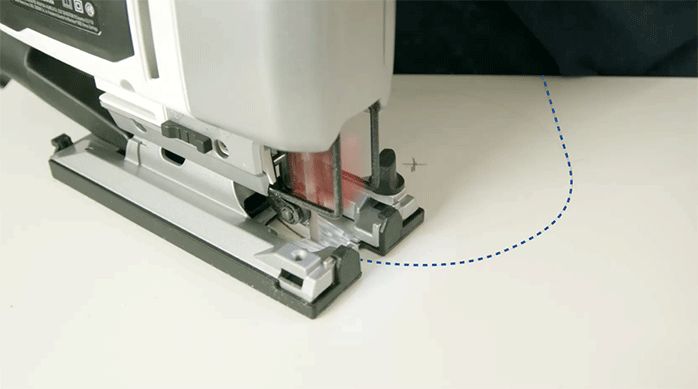 una persona corta el lateral de un mueble de melamina usando una sierra caladora.