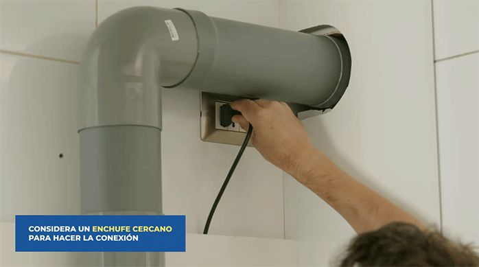un hombre enchufa la campana de extracción.