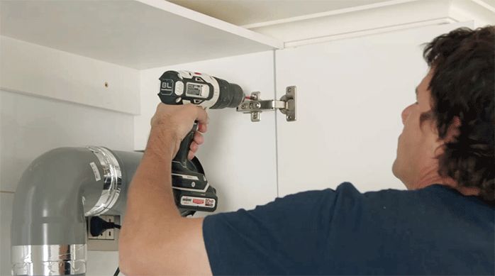 un hombre instala las puertas del mueble de melamina para la campana.