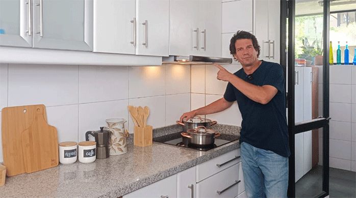 un hombre muestra una campana para cocina recién instalada.