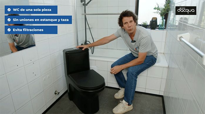 un hombre sentado en el borde de una tina, mostrando un sanitario o wc de una sola pieza, de color negro mate.