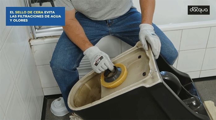 un hombre pone el sello de cera en el desagüe del sanitario.