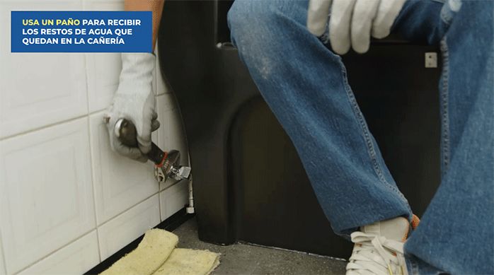 una persona instala la llave de agua en el muro del baño, que conecta con el sanitorio.