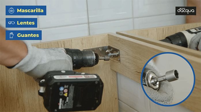 una persona atornilla el mueble vanitorio al muro del baño usando una punta hexagonal y tornillos hexagonales.