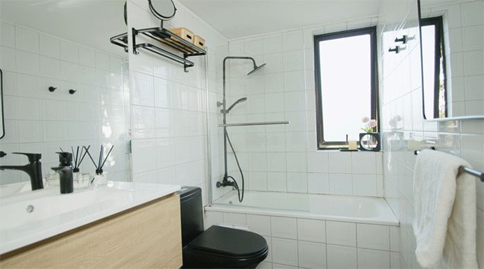 un baño recién renovado al estilo industrial, con un sanitario de una sola pieza, un espejo rectangular, accesorios de color negro mate y un vanitorio nuevo.