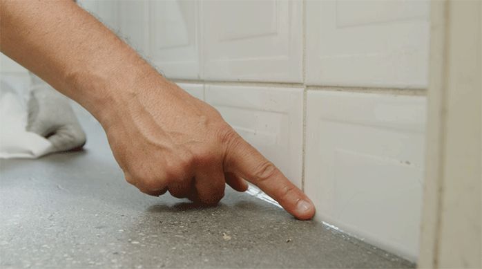 una persona pasa su dedo húmedo en el cordón de silicona para alisarlo.