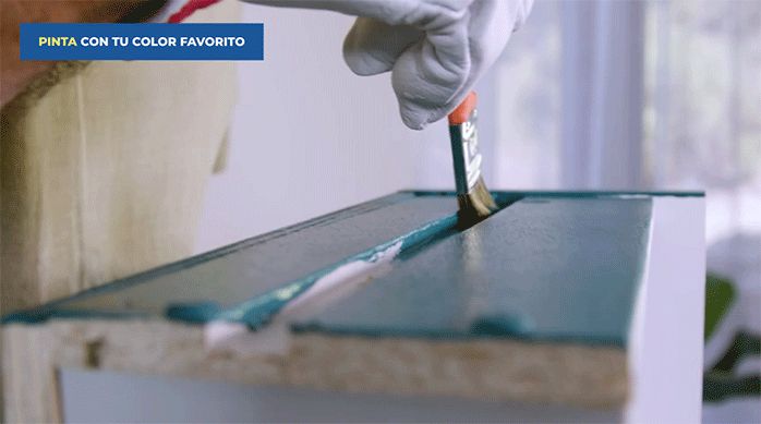 una persona pinta el cajón del velador con una brocha y pintura.