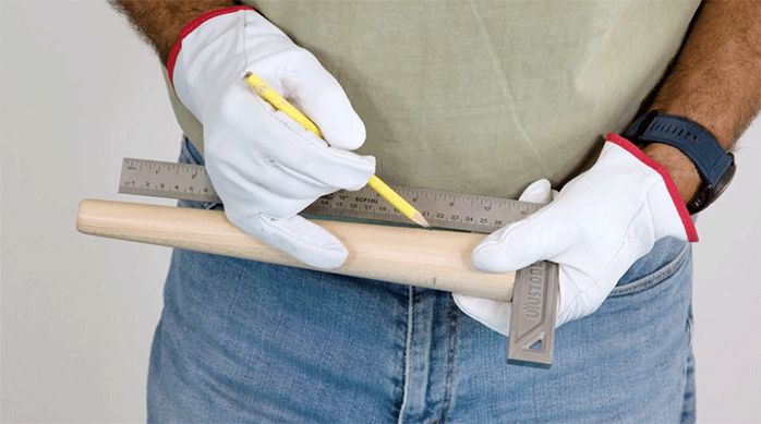 una persona mide y marca una pata de madera usando una escuadra.