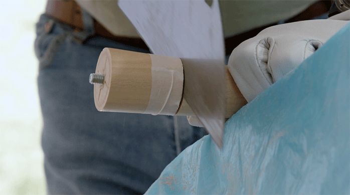 una persona corta una pata de madera usando un serrucho.