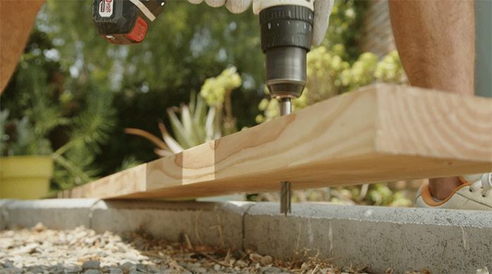 una persona perfora el extremo de un trozo de madera pino oregón.