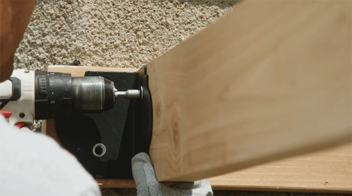 una persona fija una viga principal lateral a la viga principal del muro usando un ángulo de acero galvanizado.