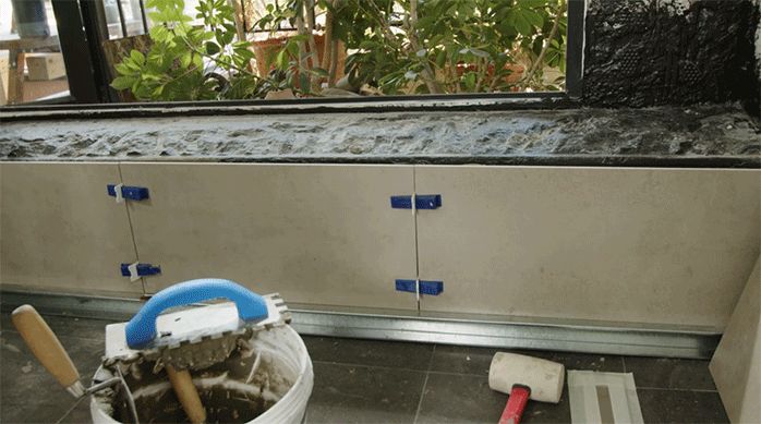un muro de ducha con palmetas de porcelanato recién instaladas, con separadores plásticos y cuñas niveladoras puestas.