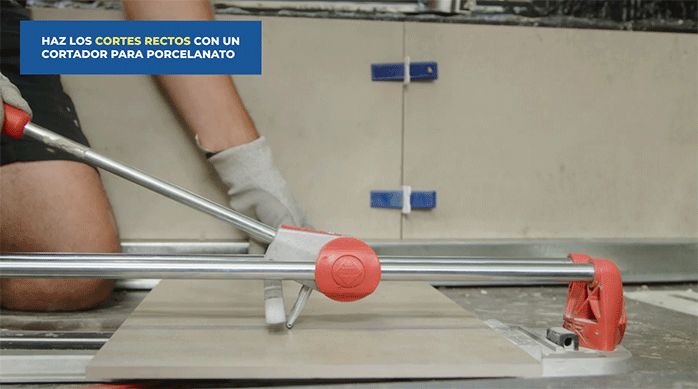 un hombre usa una cortadora para porcelanato para cortar una palmeta de porcelanato.