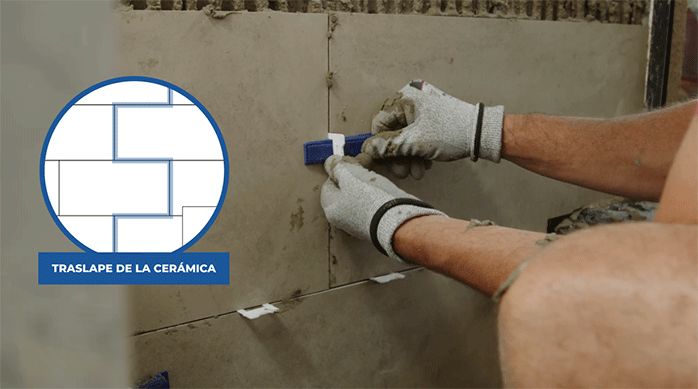 una persona pone cuñas niveladoras en los separadores plásticos que hay en las junturas entre las palmetas de porcelanato.