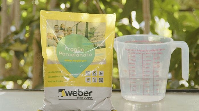 fragüe para porcelanato al lado de un recipiente medidor de agua.