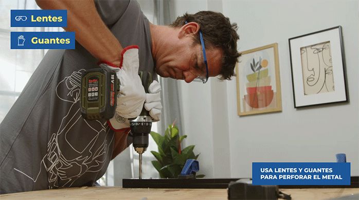 un hombre con guantes perfora un perfil metálico usando un taladro con broca para metales.