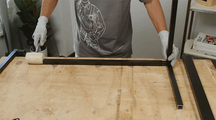 un hombre une trozos de perfiles metálicos con conectores plásticos y se ayuda con un mazo de goma para embutirlos.