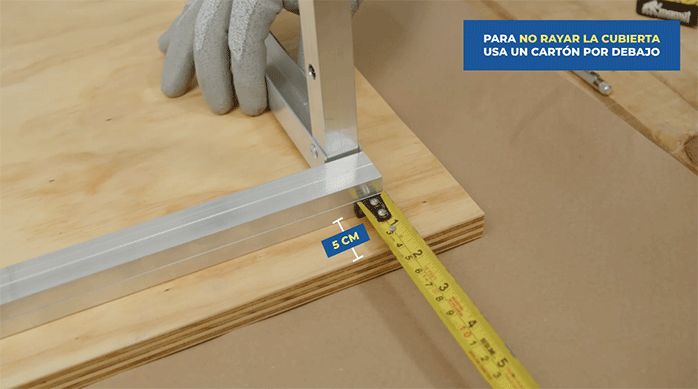 un hombre pone la base del mueble sobre la cubierta y mide 5 cm por cada lado para dejarla centrada.