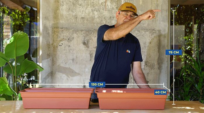 un hombre indica qué tamaño tendrá la jardinera que está a punto de construir, a partir de 4 maceteros.